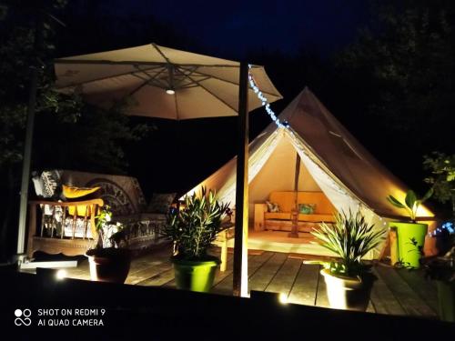 a tent with a couch and an umbrella at night at TENTE SAFARI LODGE DANS FORET LUXURIANTE in Vielle-Tursan