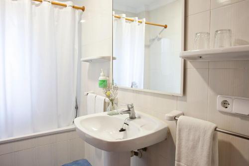 uma casa de banho branca com um lavatório e um espelho em Hotel Cala Murada em Cala Murada