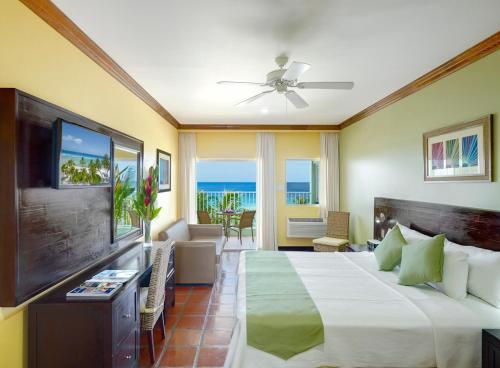 Habitación de hotel con cama y TV en Coconut Court Beach Hotel, en Bridgetown