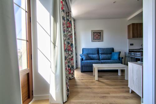a living room with a blue couch and a table at Apartamentos Arenal in Jerez de la Frontera