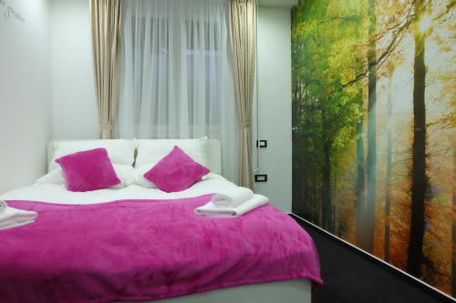 Un dormitorio con una cama con almohadas rosas y una pintura en Luwiana Suites, en Liubliana