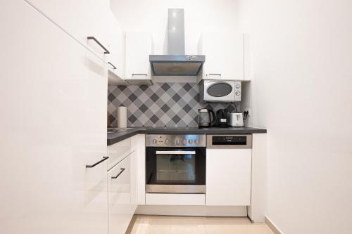Il comprend une cuisine blanche équipée d'une cuisinière et d'un four micro-ondes. dans l'établissement Apartment in the central area. 5 minute's walk to the Danube., à Vienne