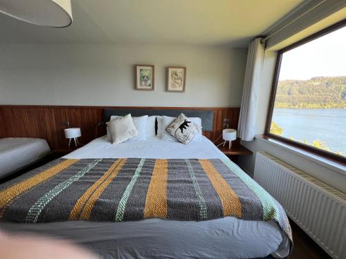 a bedroom with a bed and a large window at Hotel Boutique Cutipay in Valdivia