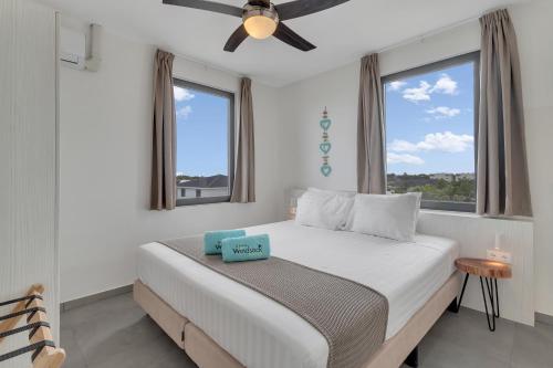 a bedroom with a bed with a ceiling fan and windows at Grand Windsock Bonaire in Kralendijk