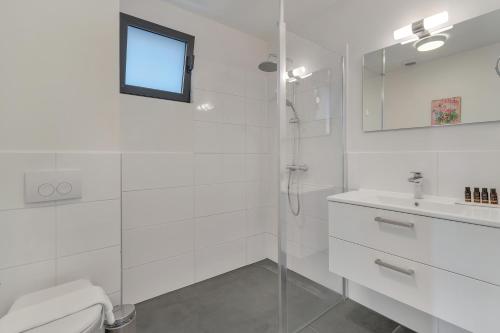 a white bathroom with a shower and a sink at Grand Windsock Bonaire in Kralendijk