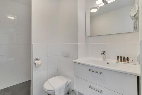 a white bathroom with a toilet and a sink at Grand Windsock Bonaire in Kralendijk