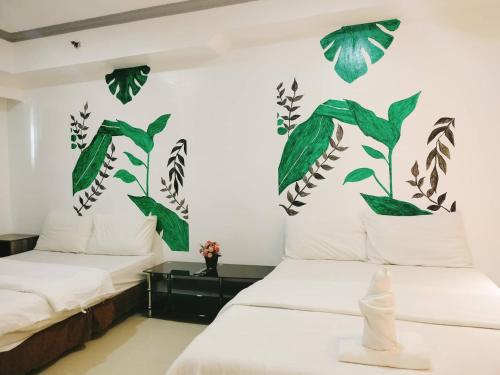 two beds in a room with green leaves on the wall at Premiere Haven MOA Staycation in Manila