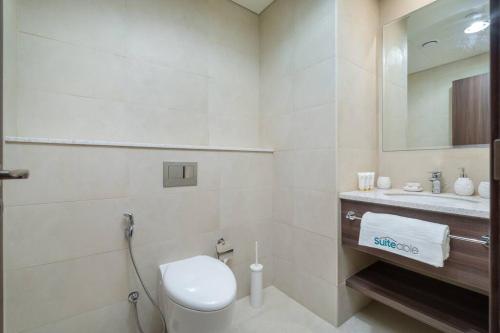 a white bathroom with a toilet and a sink at Exquisite Apartment Minutes Away from the Beach in Dubai