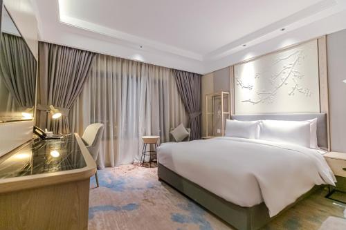 a hotel room with a large bed and a desk at Aber City Center in Hafr Al Baten