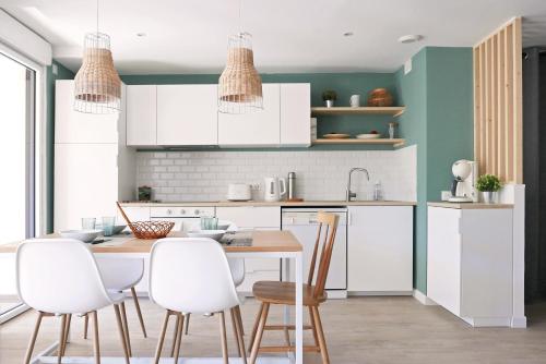 une cuisine avec des armoires blanches et une table et des chaises dans l'établissement Bandol AZUR - 2 chambres, balcon, bord de mer, wifi, climatisé et parking privé, à Bandol