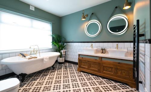 a bathroom with two sinks and a tub and two mirrors at The Bear in Bath