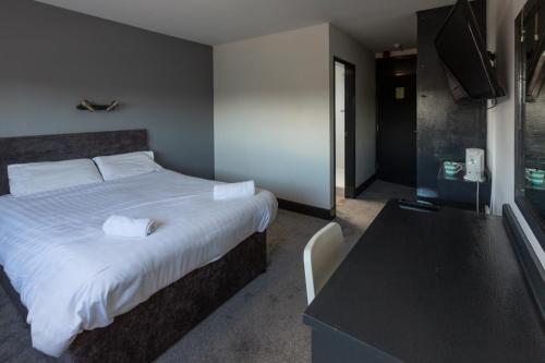 een slaapkamer met een bed, een tafel en een televisie bij Pelham Hotel in Immingham