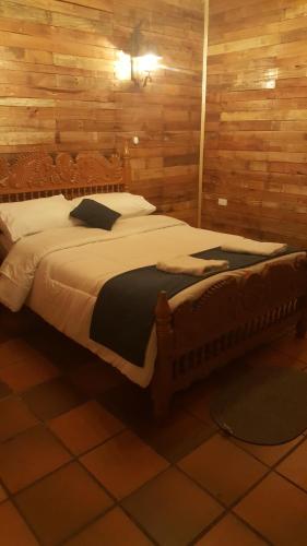 Cama grande en habitación con paredes de madera en Hotel Chalet Casa Grande, en Nobsa