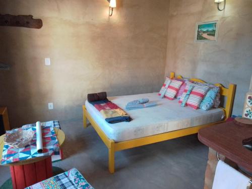 um quarto com uma cama amarela com almofadas coloridas em Chalé Caiçara em Carrancas