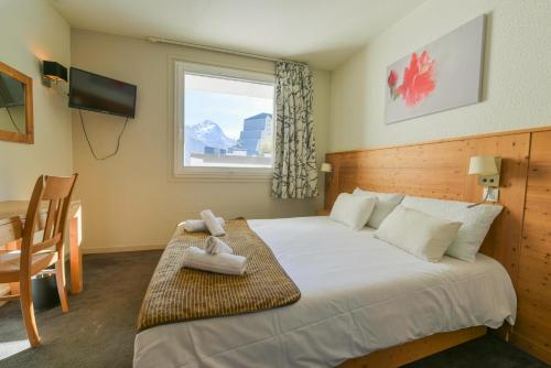 a bedroom with a bed and a desk and a window at Hotel la Brunerie in Les Deux Alpes