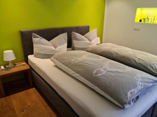 łóżko z białymi poduszkami i zieloną ścianą w obiekcie Ammann Marika w mieście Vandans