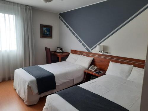 a hotel room with two beds and a window at Hotel Runcu Miraflores in Lima