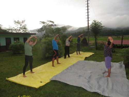 um grupo de pessoas fazendo yoga em um cobertor amarelo em Gorkha Organic Agro Farm em Gorkhā