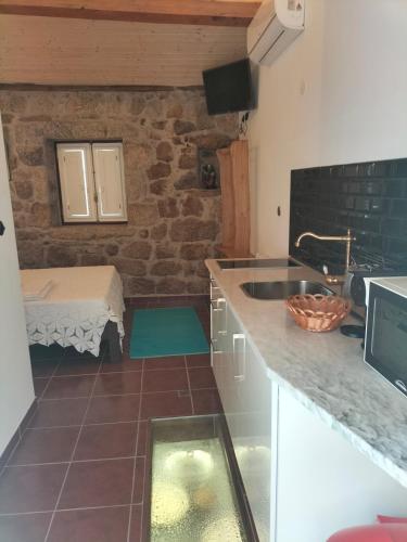 a kitchen with a sink and a bed in a room at Casa da Vila in Sortelha