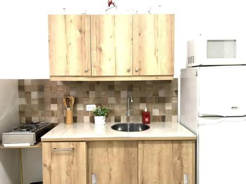 a kitchen with wooden cabinets and a sink and a refrigerator at Los Soles Suite Mall del Sol Guayaquil Airport in Guayaquil