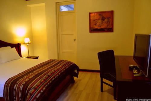 a hotel room with a bed and a desk and a television at Hotel Cuenca in Cuenca
