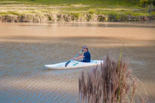 a man is sitting on a kayak in the water at Recanto do Vale Glamping in Pomerode