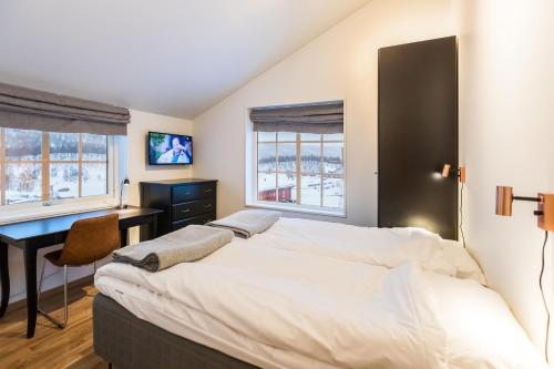 ein Schlafzimmer mit einem großen Bett und einem Schreibtisch in der Unterkunft Ramundberget Skarsgården in Bruksvallarna