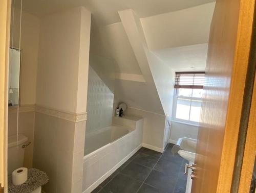 a bathroom with a bath tub and a toilet at Caldey View- a beautiful flat in the heart ofTenby in Tenby