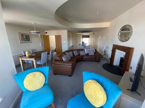 a living room with a couch and blue chairs at Caldey View- a beautiful flat in the heart ofTenby in Tenby