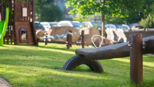 a park bench with a playground in the grass at Boutique Hotel Soyka in Špindlerův Mlýn
