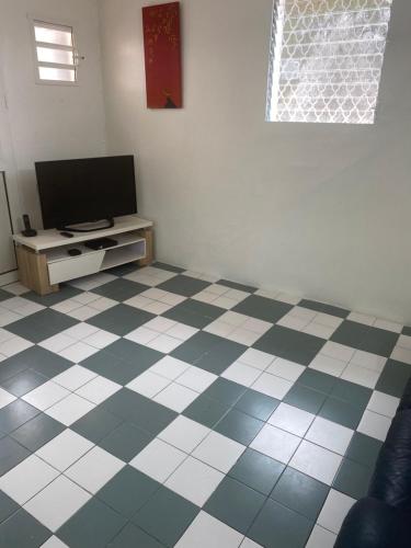 a living room with a television and a checkered floor at Appartement Orchidée 3 in Fort-de-France