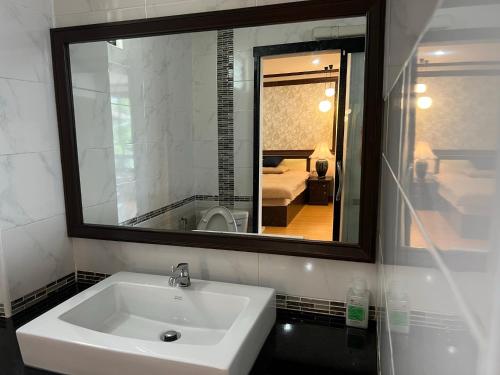 a bathroom with a white sink and a mirror at October Hostel ChiangMai in Chiang Mai