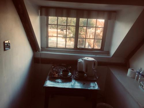 Tudor House - Double Room - Shared Bathroom في Goffs Oak: طاولة صغيرة مع ميكروويف ونافذة