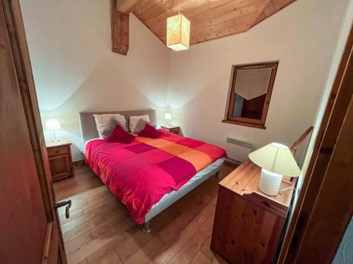 a bedroom with a bed with a red comforter at Chalet l'Arnica in Les Gets