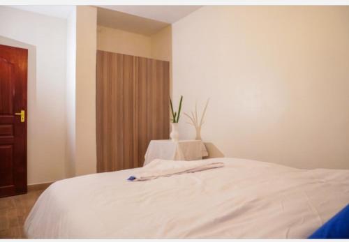 a bedroom with a white bed with a vase on it at RUPITAL SUITE's in Nakuru