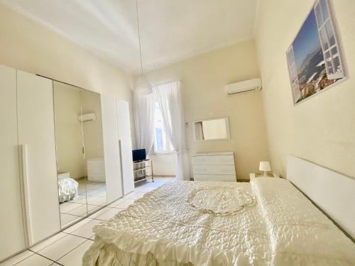 Habitación blanca con cama y espejo en Summerhome, en Nápoles