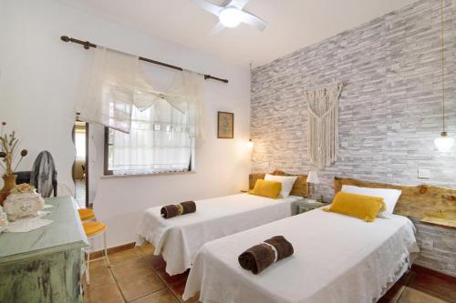 sypialnia z 2 łóżkami i ceglaną ścianą w obiekcie Casa Rústica w mieście Silves