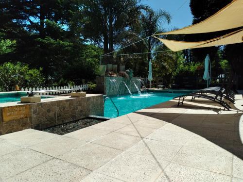 a swimming pool with a fountain and a umbrella at Pualy Resort & Spa in Belén de Escobar