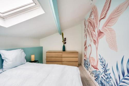 a bedroom with a white bed with a tropical mural on the wall at Bordeaux : superb apartment near St-Jean station in Bordeaux