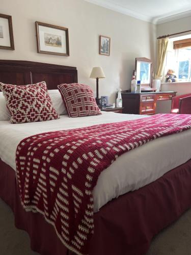 a large bed with a red and white blanket on it at John Barleycorn in Duxford