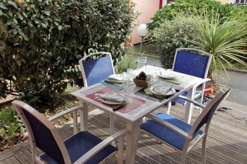 a white table and chairs on a deck at 36 m with terrace and pool near beach in Soustons