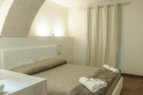 een witte kamer met een bed met handdoeken erop bij Little House in Altamura