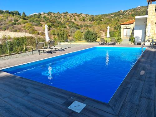 ein blauer Pool mit Stühlen und ein Haus in der Unterkunft Gaia Residence, Peristerona, Polis Chrysochous in Paphos City