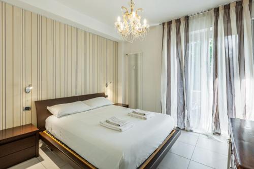 1 dormitorio con 1 cama blanca grande con lámpara de araña en Easylife - Spacious apartment in Maciachini, en Milán