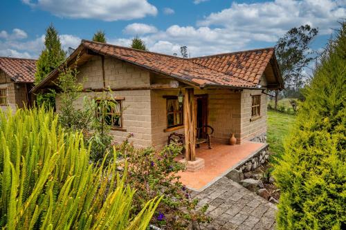 uma pequena casa de tijolos com um alpendre num jardim em Hacienda Turistica Intihuatana em San Fernando