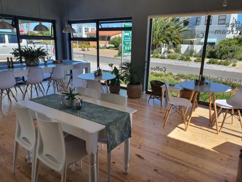 un restaurante con mesas, sillas y ventanas en Kaijaiki Country Inn and Restaurant, en Yzerfontein