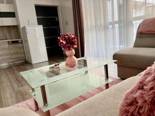 a living room with a glass table with a vase on it at SunSuite Szeged in Szeged