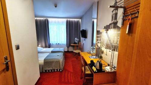 Habitación de hotel con cama y escritorio. en Hotel Malinowski Economy, en Gliwice