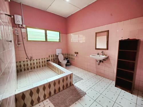 różowa łazienka z toaletą i umywalką w obiekcie Tumi Hostel w mieście Kumasi