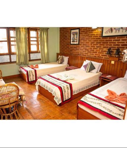 Cette chambre comprend 3 lits et un mur en briques. dans l'établissement Shiva Guest House 2, à Bhaktapur